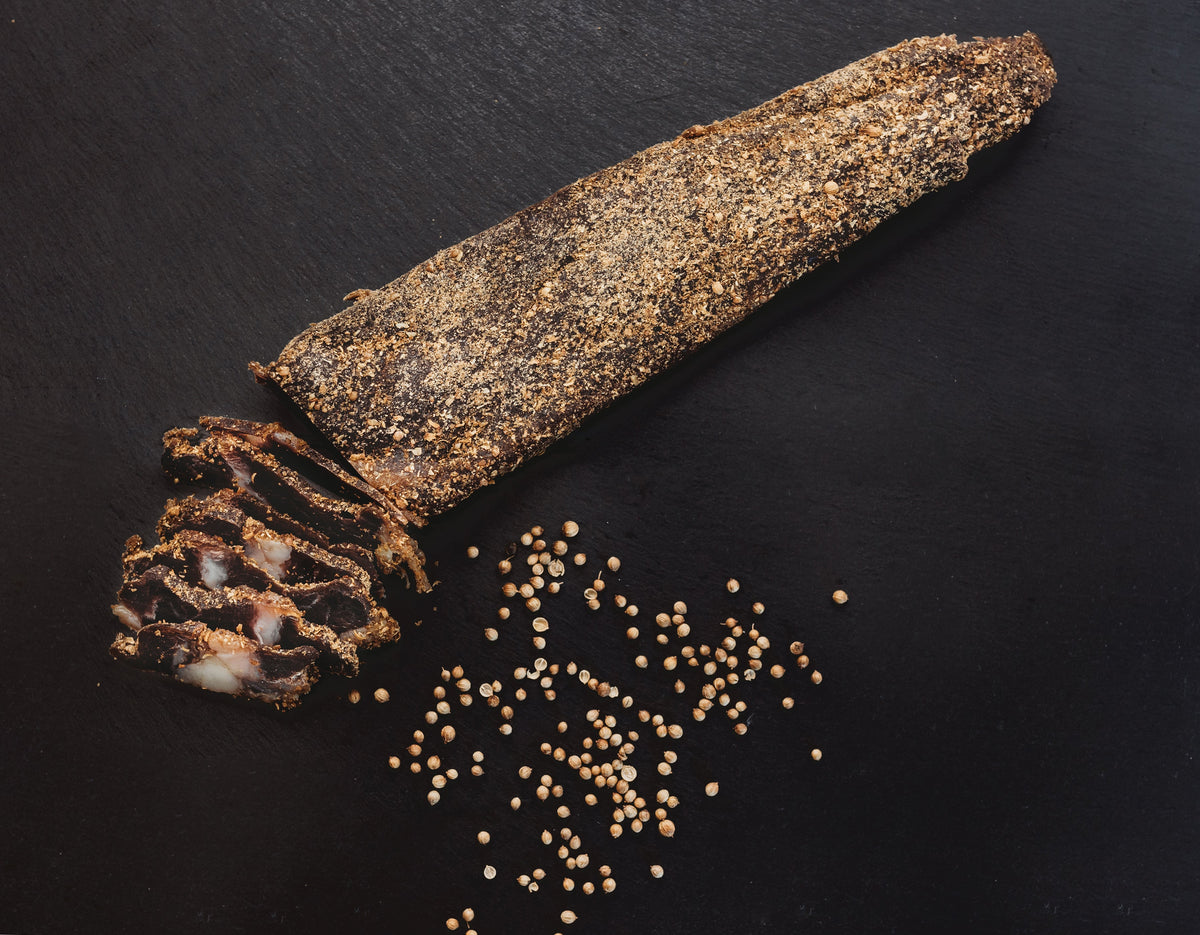 A whole biltong slab on black slate with scattered coriander