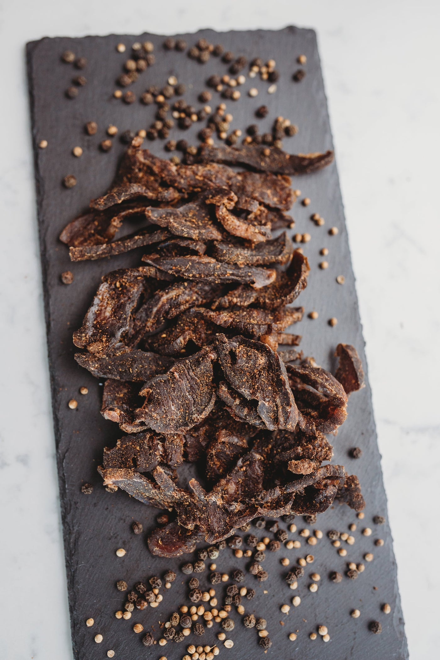 Sliced biltong spread across a grey stone board
