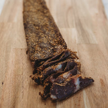 A biltong slab beside slices on a wooden board